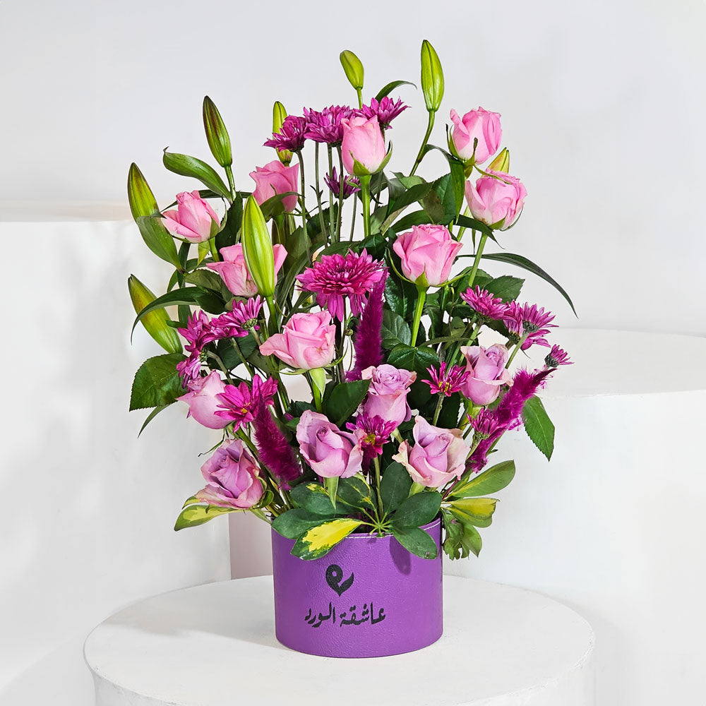 a box that contains purple roses, chrysanthemums, and lilies